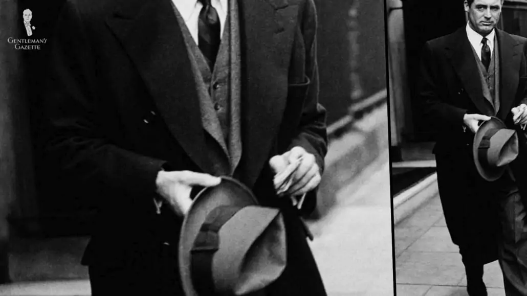 Cary Grant in a three-piece suit in mid-gray flannel with a darker overcoat and a white shirt, shoes, and hat.