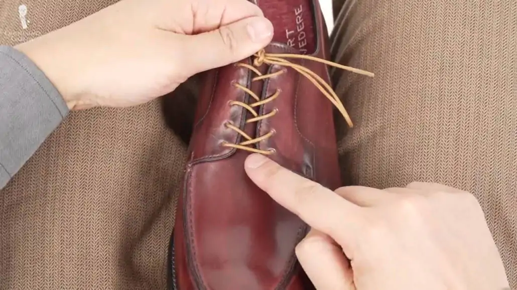 Raphael pointing to a finished cross lacing on a derby shoe.