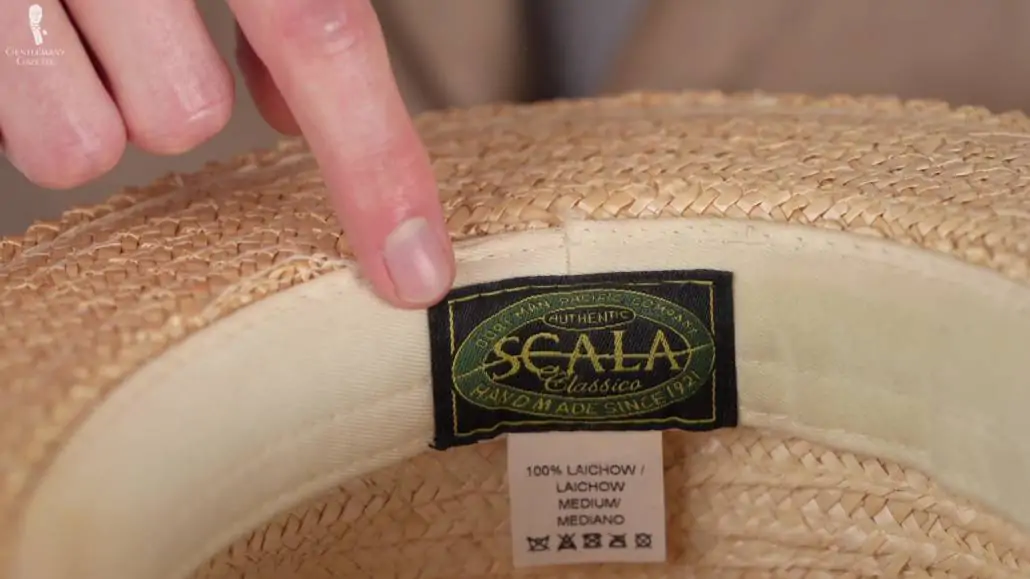 Preston pointing to a straw hat's label. 