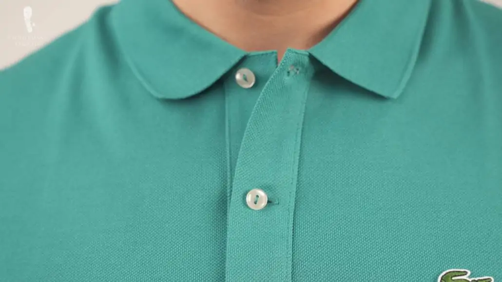A turquoise Lacoste shirt with two buttons and two buttonholes.