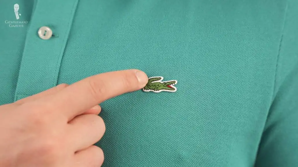 Raphael pointing to the Lacoste logo on a turquoise shirt. 