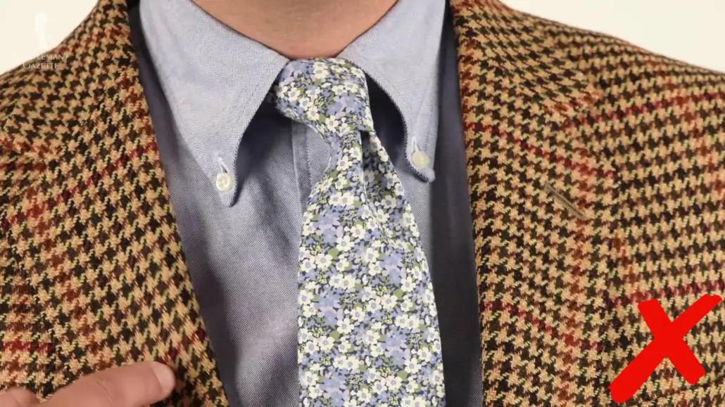 Raphael wearing a brown houndstooth jacket paired with a light gray OCBD shirt and light blue and white floral tie. 