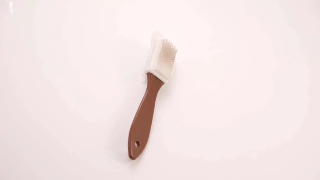 A white suede brush with brown handle.