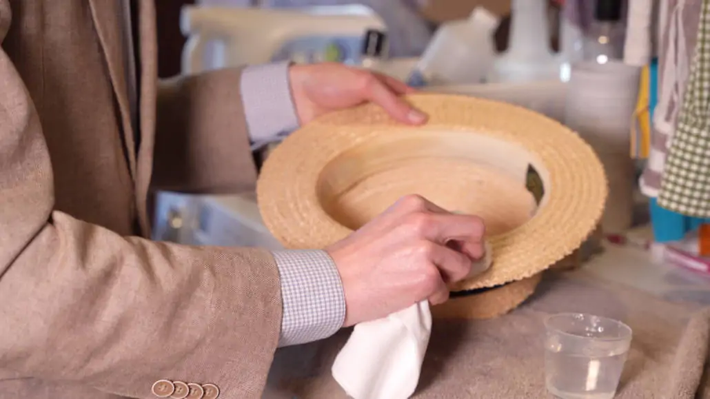 Preston wiping a straw hat with a white cloth.