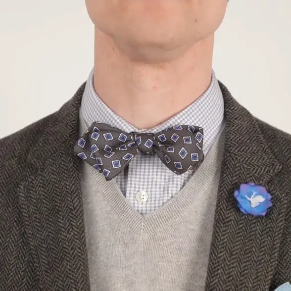 Preston wearing a gray knit vest and bow tie and combined with a blue boutonniere.