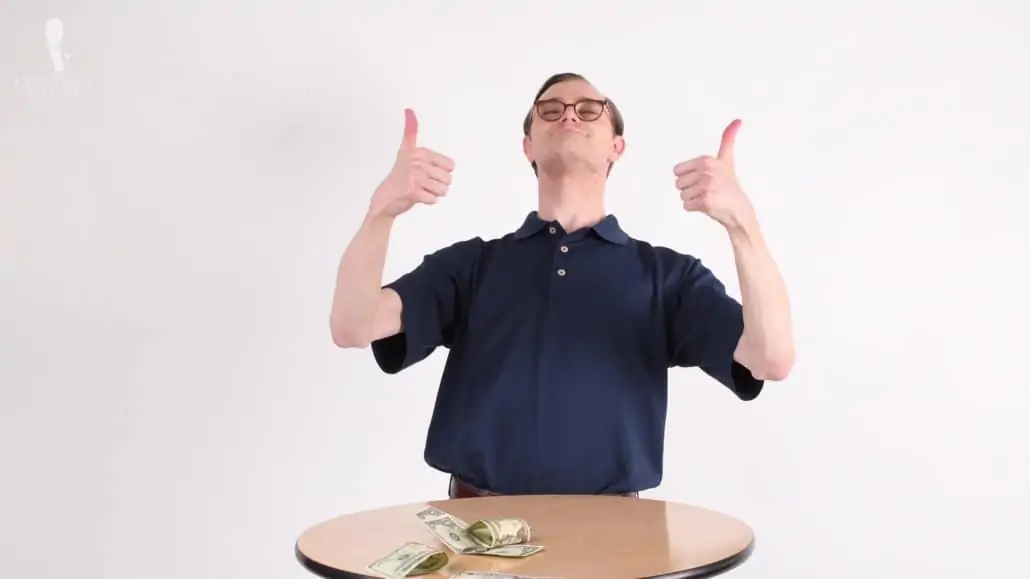 Preston with two thumbs up and a pile of money on a table.