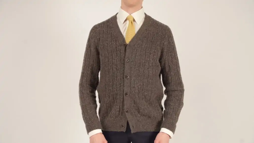 Preston wearing brown knit sweater and yellow knit tie