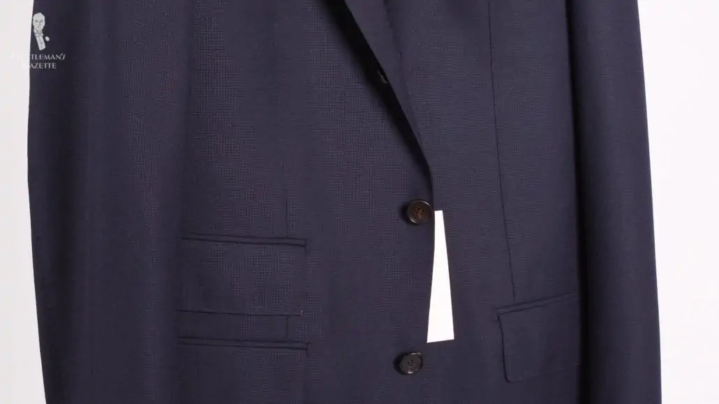 A navy suit with 3 buttons, with the middle button closed.