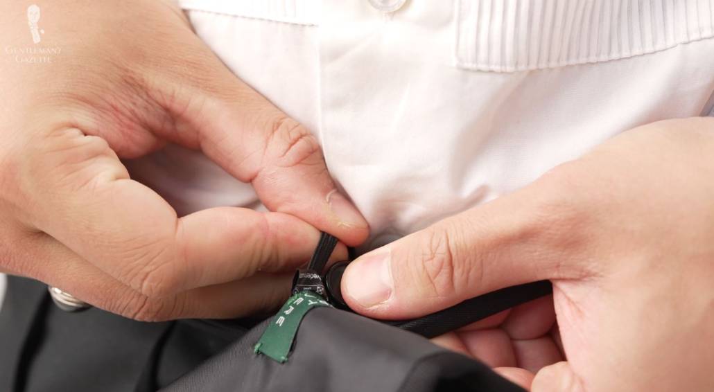 A cummerbund should have a loop that you can fasten to your trousers so it stays in place.