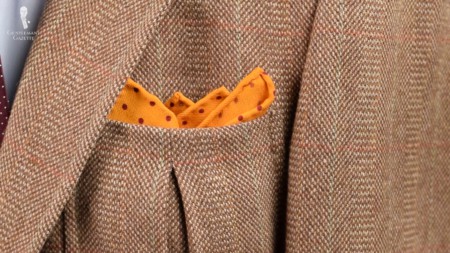 A jacket pocket with an orange polka dot pocket square