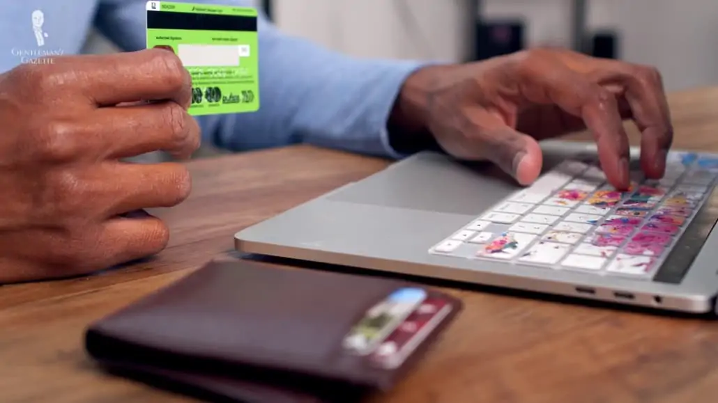 A man holding a credit card preparing to make an online purchase.