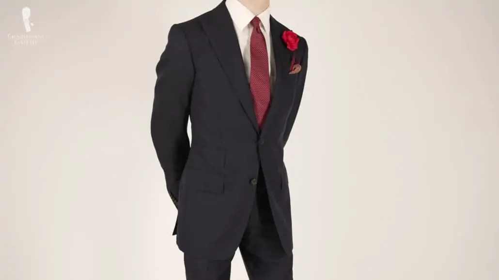 Preston wearing a black suit paired with a red micro polka dot tie red rose boutonniere and printed pocket square.