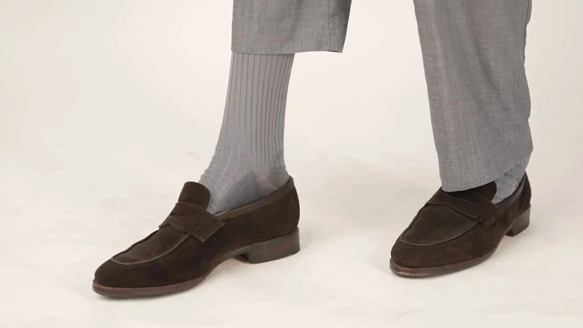 Preston wearing chocolate brown suede loafers paired with shadow-striped socks in light blue and gray.
