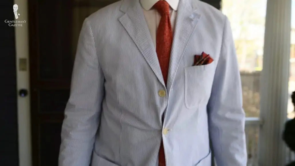 Raphael wearing a seersucker suit from Polo Ralph Lauren accessorized with Orange Red Mottled Knit Tie and red pocket square from Fort Belvedere.