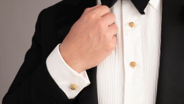 View of a gentleman's hand clasping the lapel of his jacket while wearing black tie