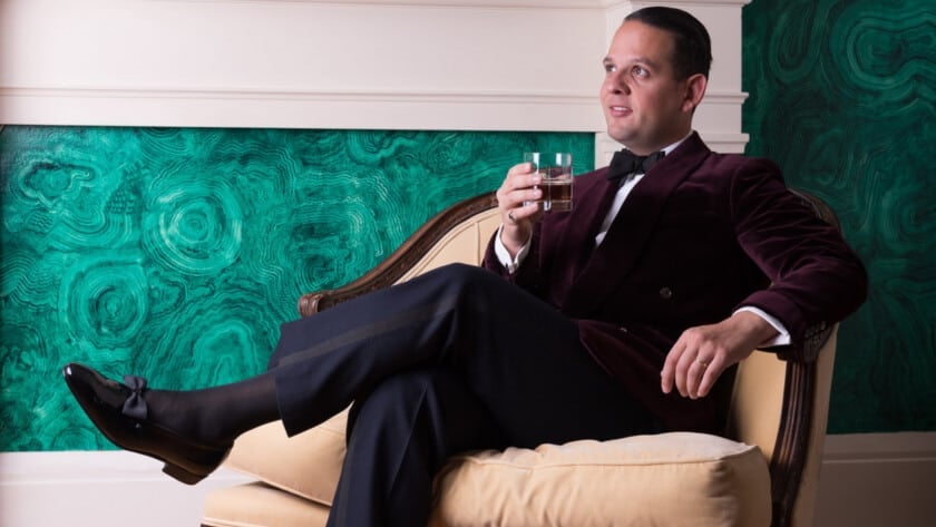 Black Tie Buying Guide Featured Image Raphael relaxs at home in a red velvet dinner jacket and midnight blue trouers