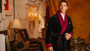 Photograph of a man in a domestic setting wearing a black and red smoking jacket
