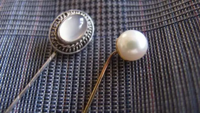 A stick pin is inserted through both the shirt and the tie