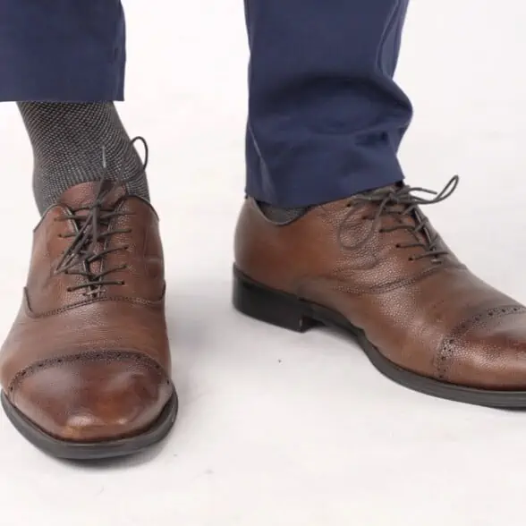 The socks Kyle is wearing matches the brown brogue dress shoes.