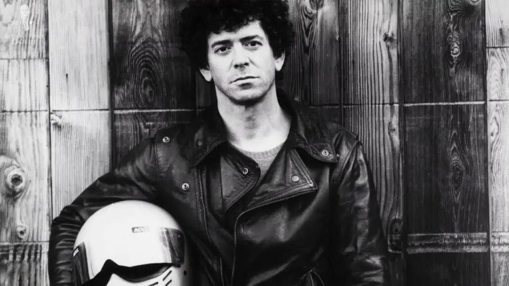 Lou Reed wearing a Schott Perfecto jacket while holding a motorcycle helmer