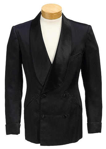 A photograph of a dark navy smoking jacket with shawl collar and frog closure detailing. A navy silk smoking jacket worn by Fred Astaire while filming Three Little Words (1950). Source: Bonhams Auction House.