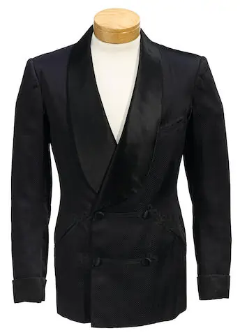 A photograph of a dark navy smoking jacket with shawl collar and frog closure detailing. A navy silk smoking jacket worn by Fred Astaire while filming Three Little Words (1950). Source: Bonhams Auction House.