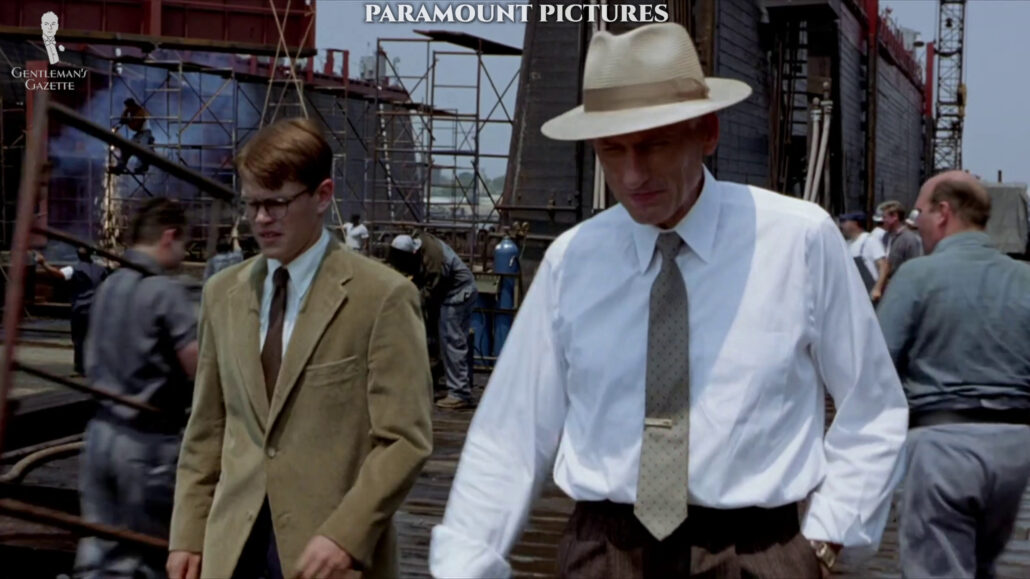 Tom walking at the shipyard with Herbert Greenleaf wearing a two-button, corduroy jacket, and printed Macclesfield tie that is around eight cm or two and a half or 3 inches width.