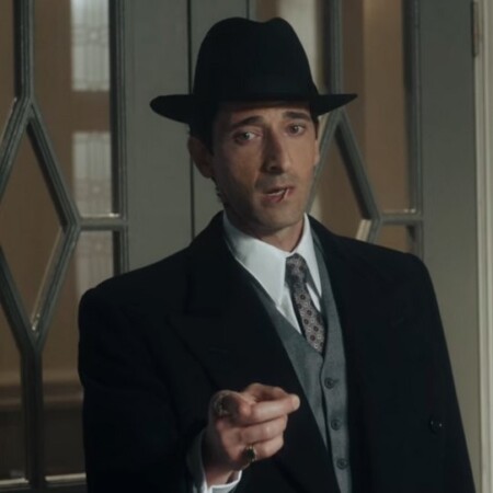 A photograph of Peaky Blinders character Luca Changretta in a dark suit and fedora. 