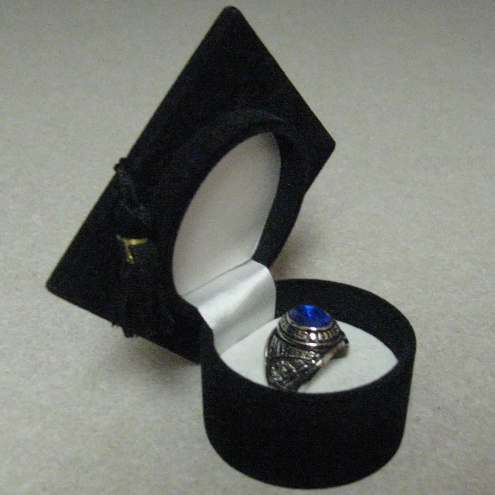 A photograph of a silver class ring with a blue stone