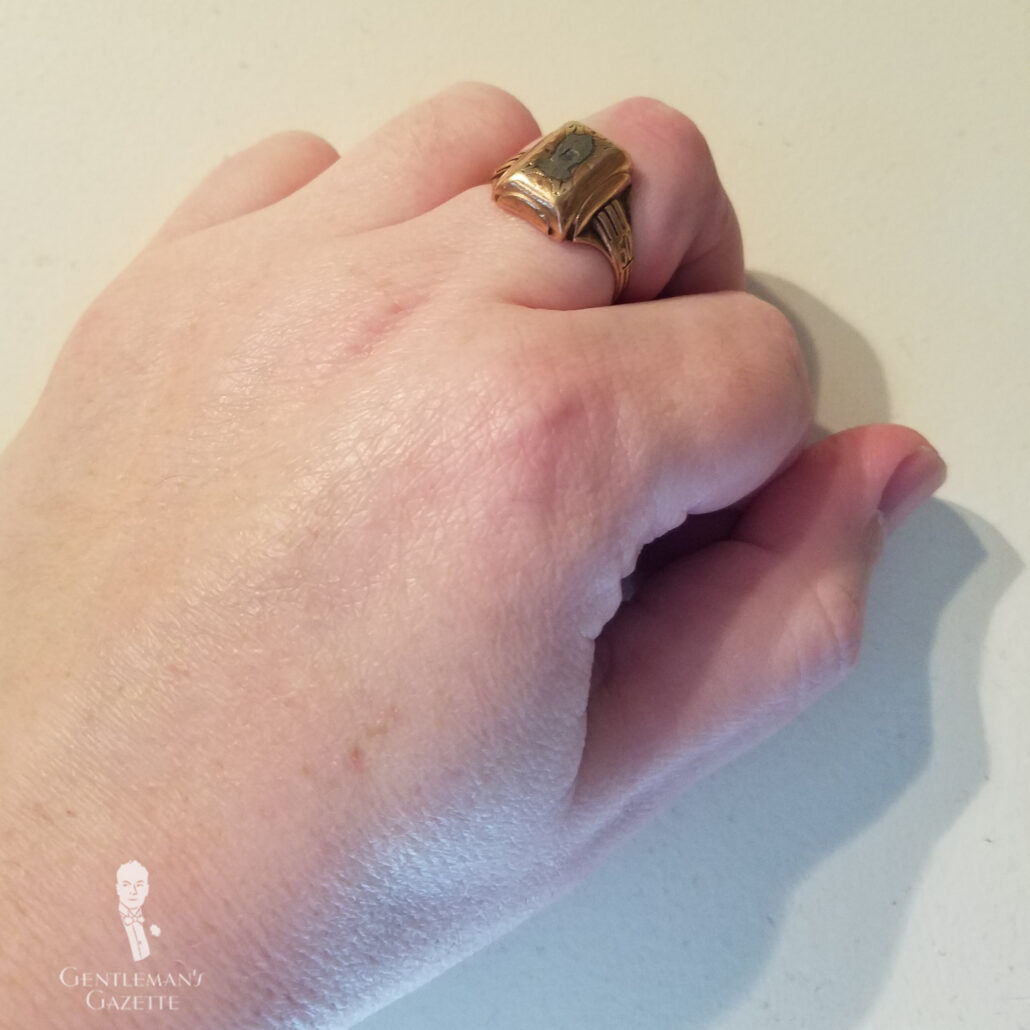 A hand with a copper ring on the middle finger