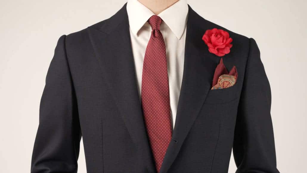 Navy suit with silk Jacquard white polka dots, silk-wool pocket square, and red camellia boutonniere.