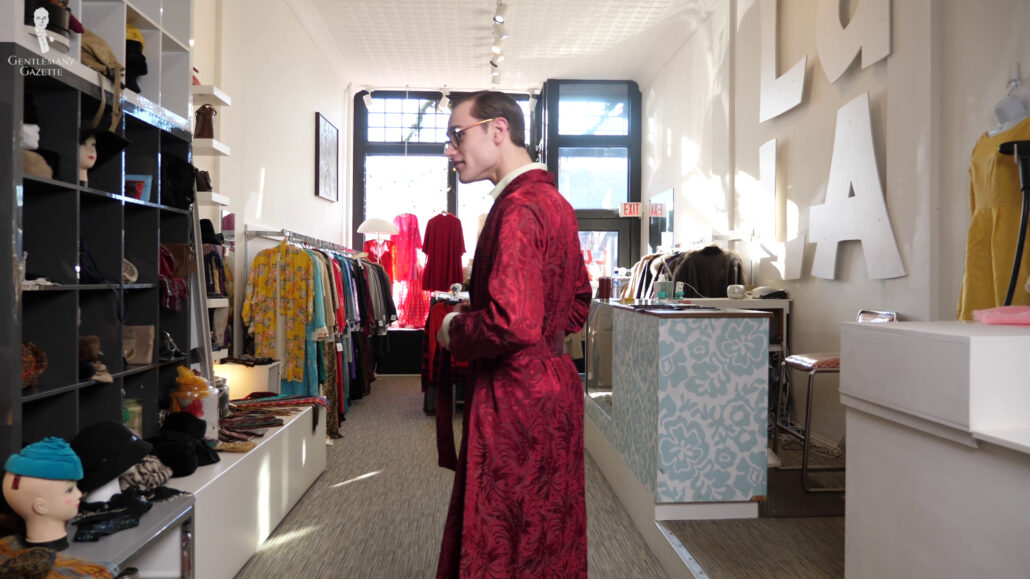 Preston trying on a vintage burgundy silk dressing gown in a vintage store.