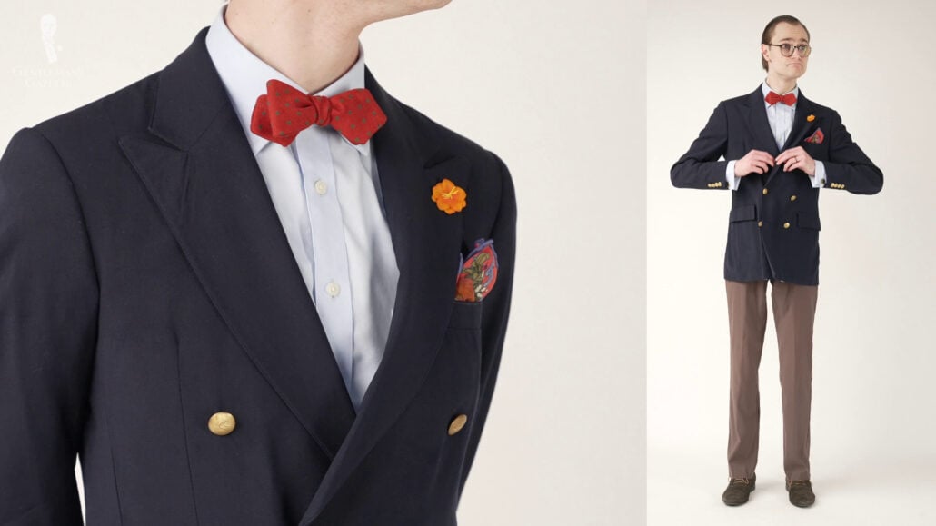 Preston wearing a plain blue French cuffed shirt and a navy blue blazer with gold buttons paired with a brown with a reddish undertone trousers.