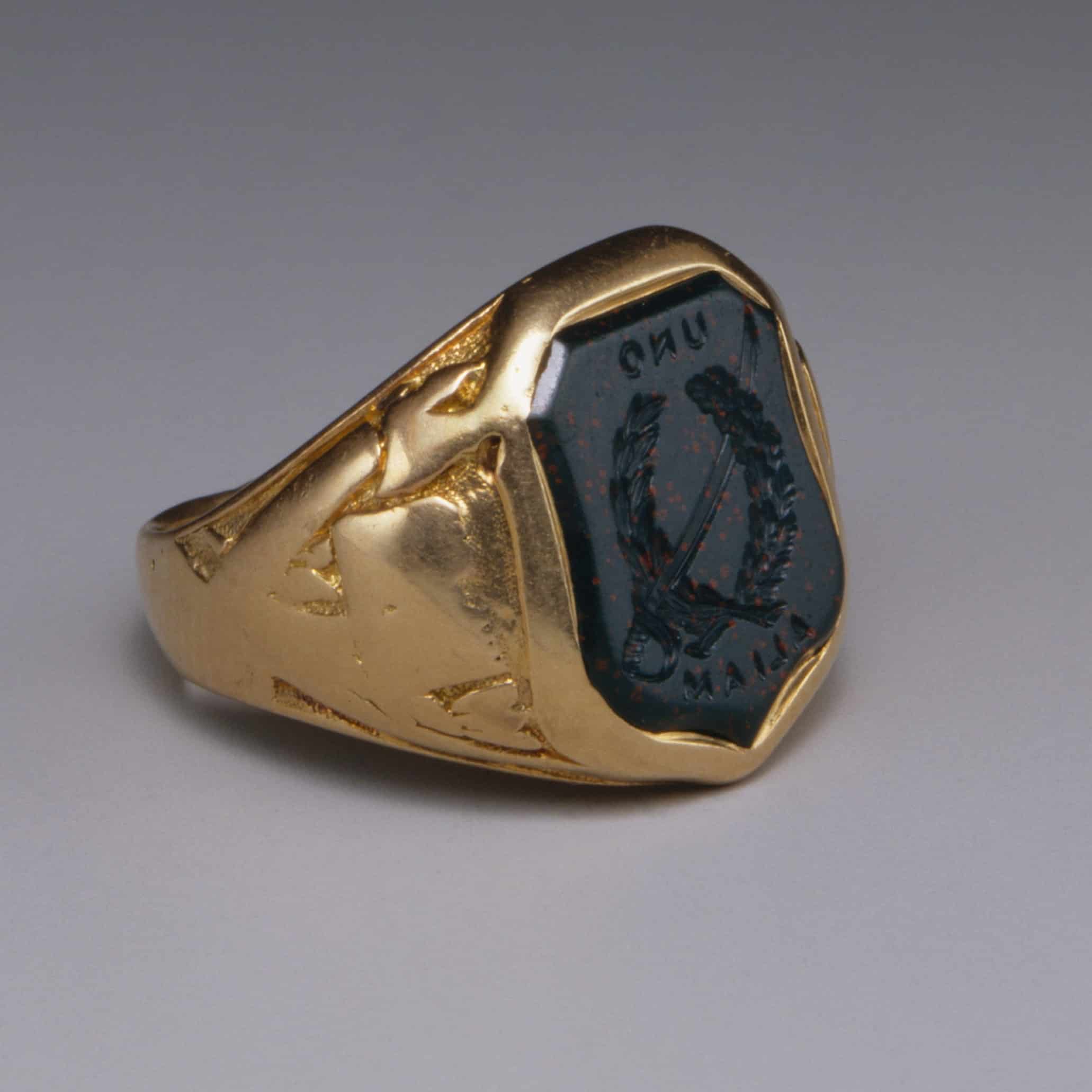 A gold glass ring with a dark stone insert