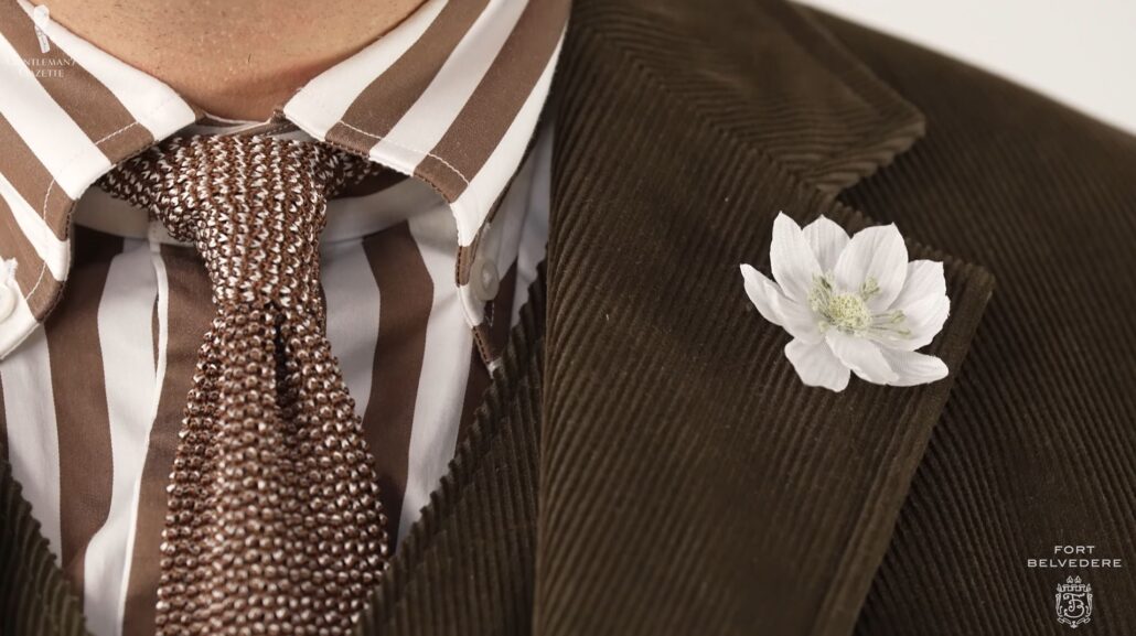 The complementing brown and beige knit tie and white and green lotus flower boutonniere up close