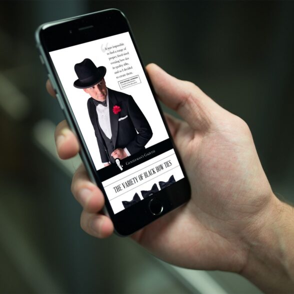 A close-up image of a hand holding a smartphone, displaying the Gentleman's Gazette's Black Tie Pocket Guide