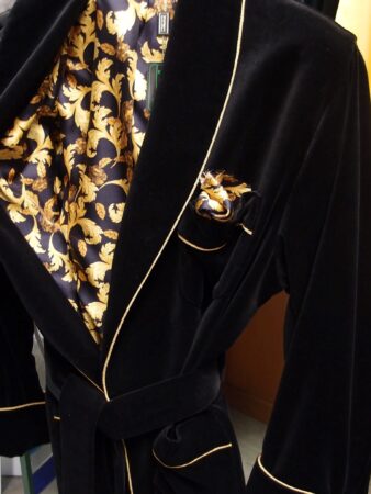 A photograph of a black smoking jacket with gold trim