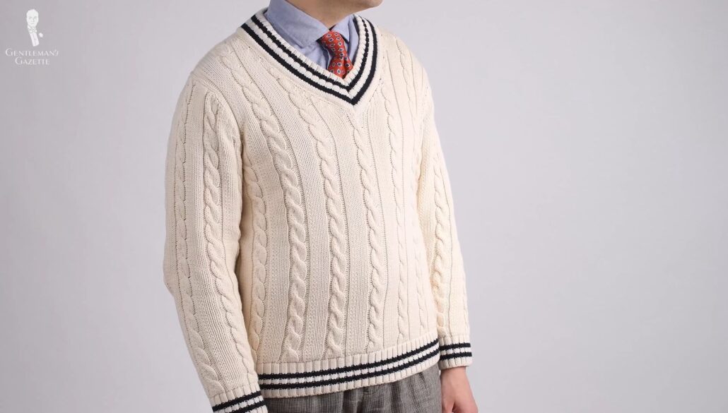 Raphael wears a white tennis sweater with navy accents