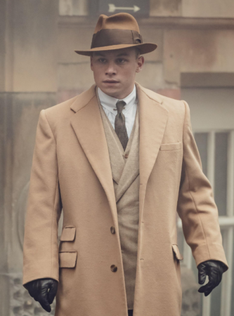 Peaky Blinders character Michael Gray in a brown fedora with a camel-hair coat.