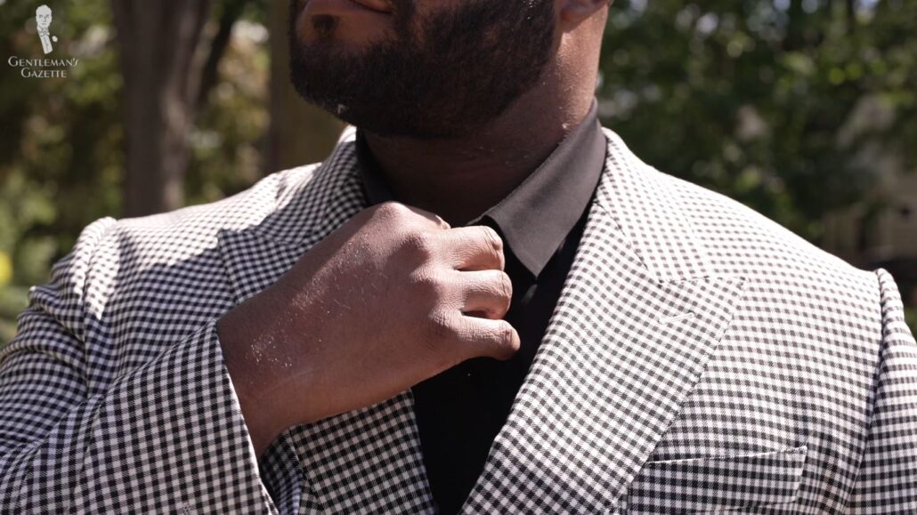 Kyle wears a check-patterned jacket with his black dress shirt