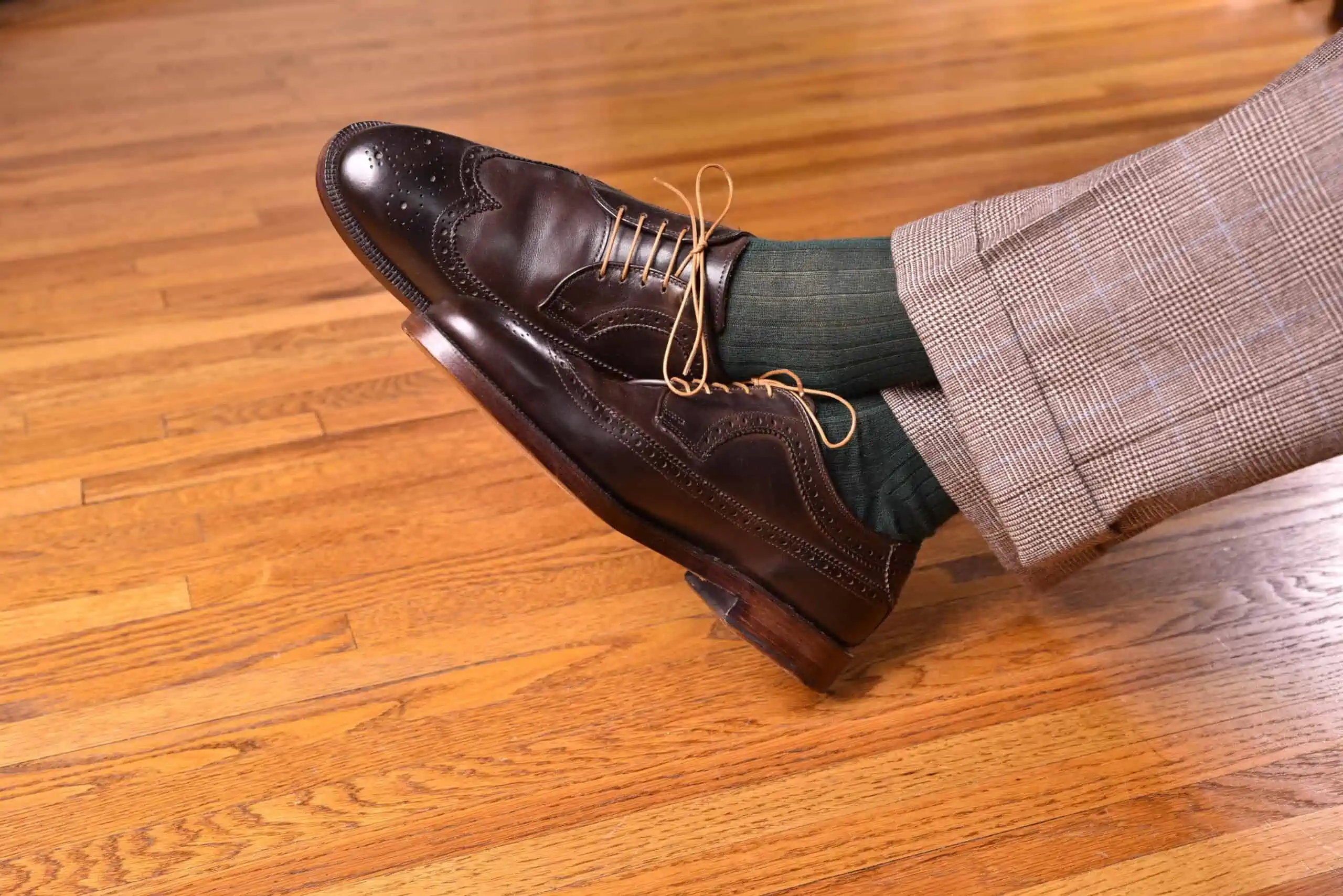 Dark brown cordovan shoes paired with green socks and checked trousers