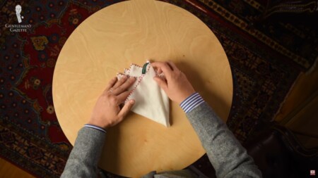 Folding the left corner of a pocket square to the right