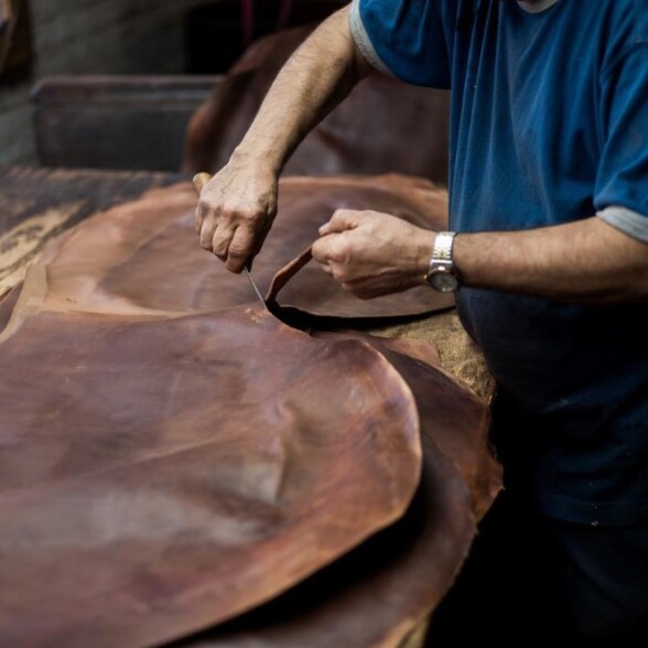 A worker uses a knife to cut the cordovan leather in the Horween tannery