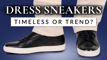 Kyle wears a pair of navy blue and white dress sneakers with stone-colored chinos.