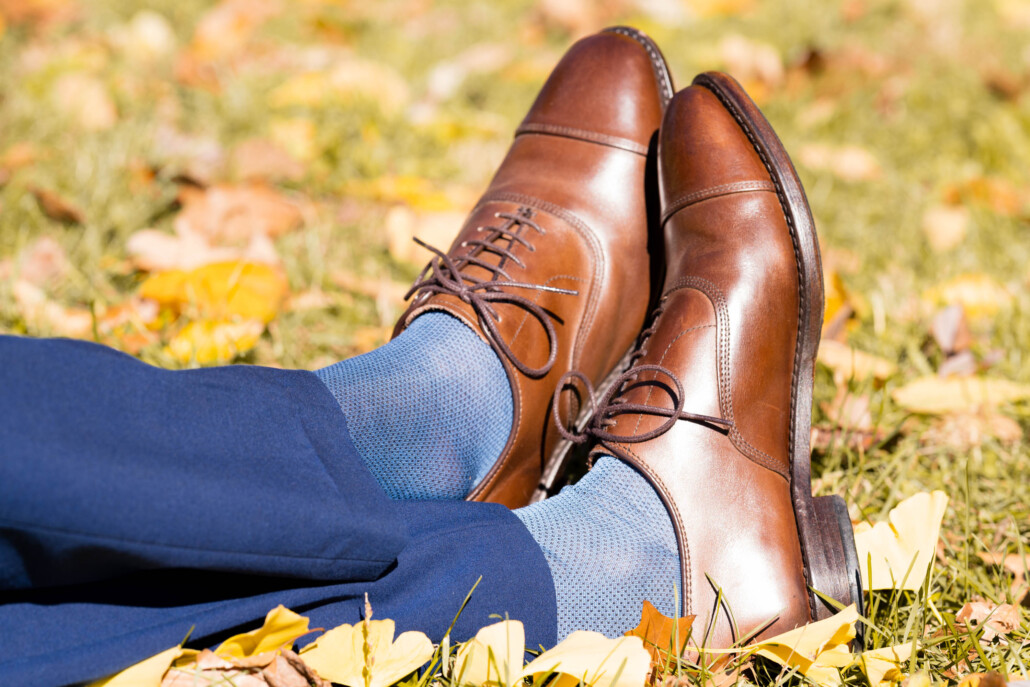 Brown cap toe Oxford shoes worn with blue pants and socks