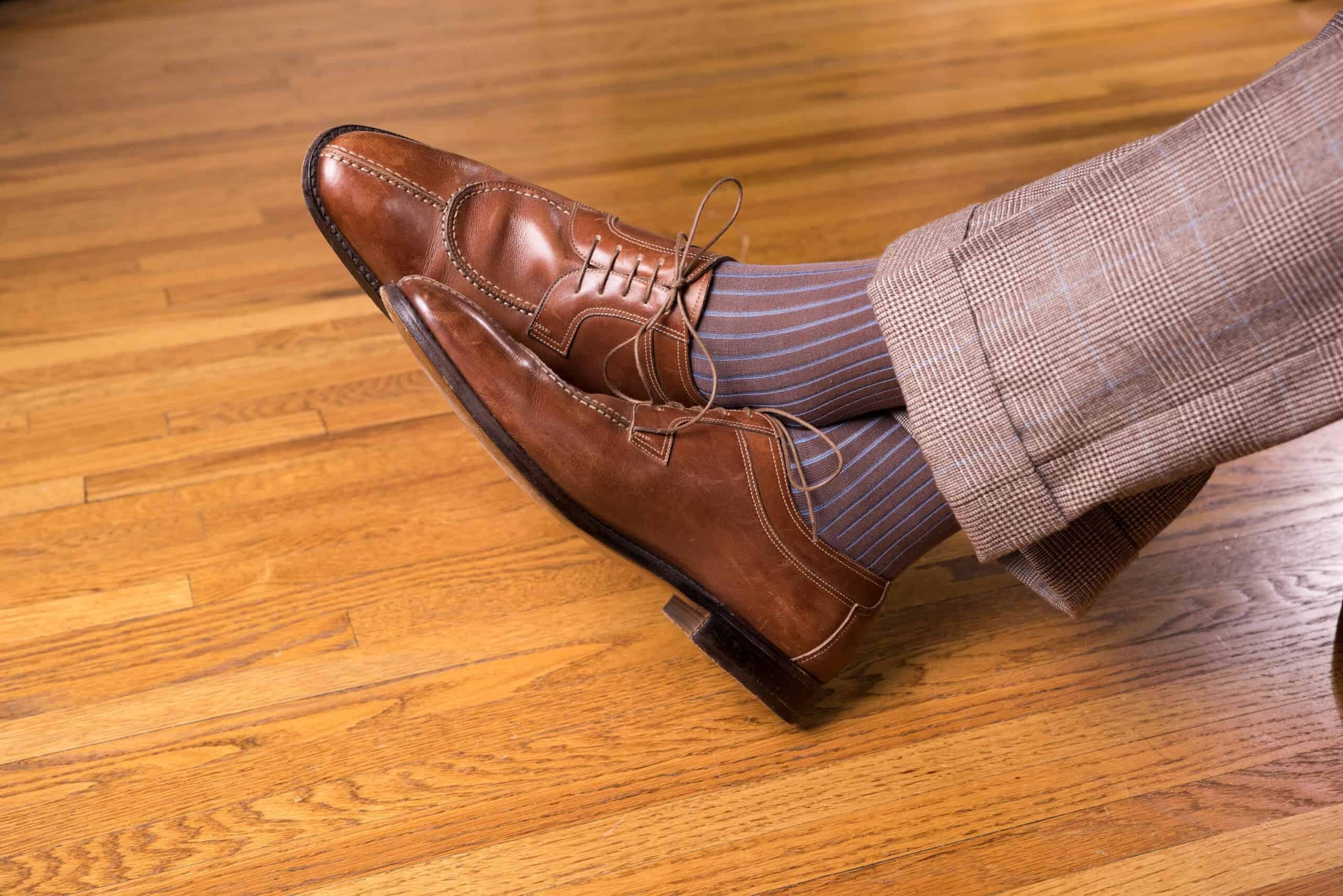 Mid brown Derby shoes with brown and blue socks and checked pants
