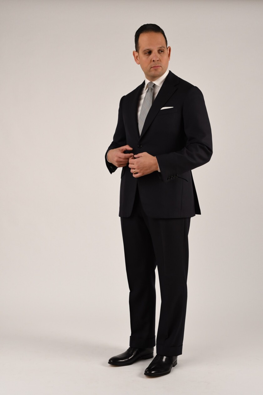 Raphael wears a navy suit with a pair of black wholecut Oxfords for a very formal look