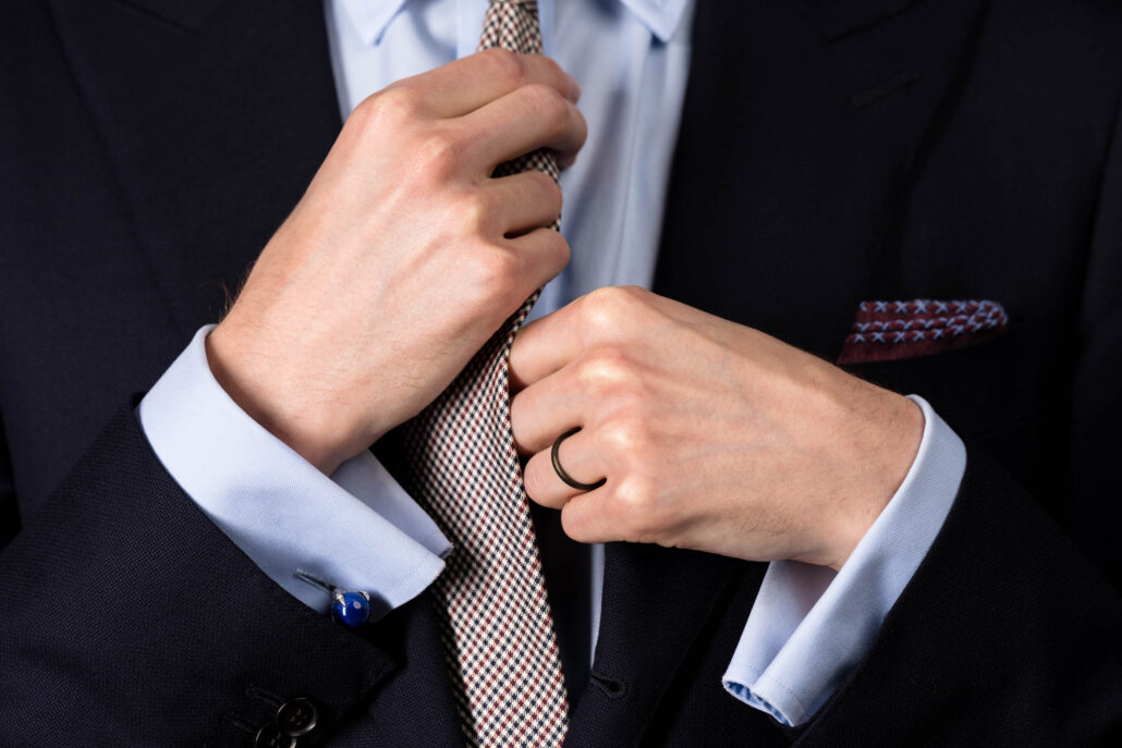 Hands adjust a red and blue tie 