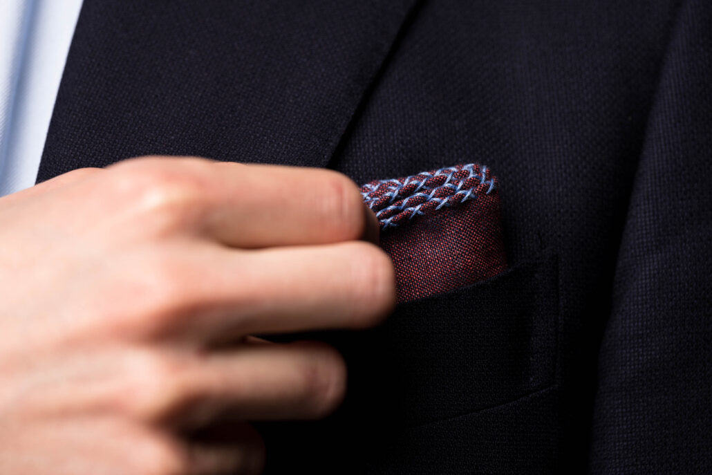 A photograph of a burgundy pocket square with blue x stitching 