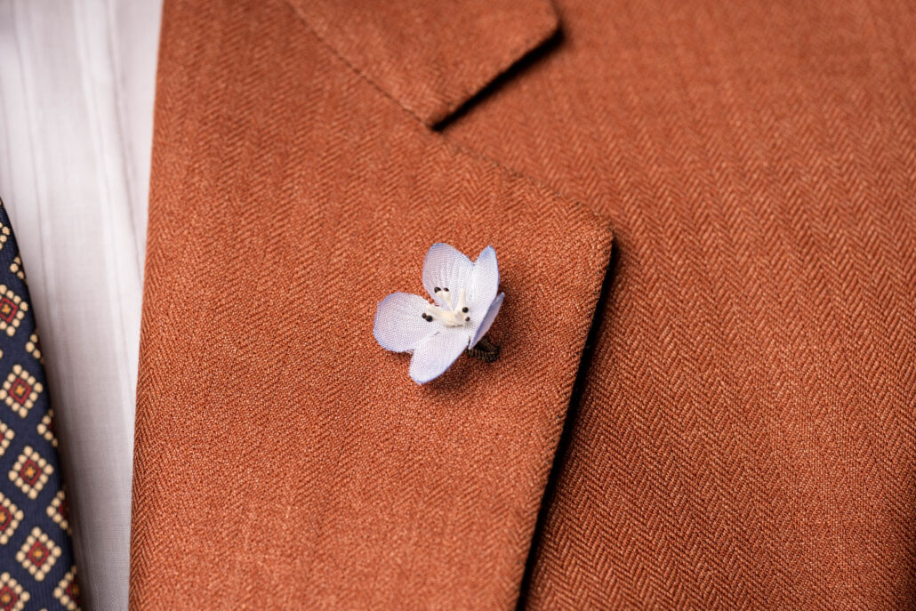 A pale blue flower worn on an orange suit